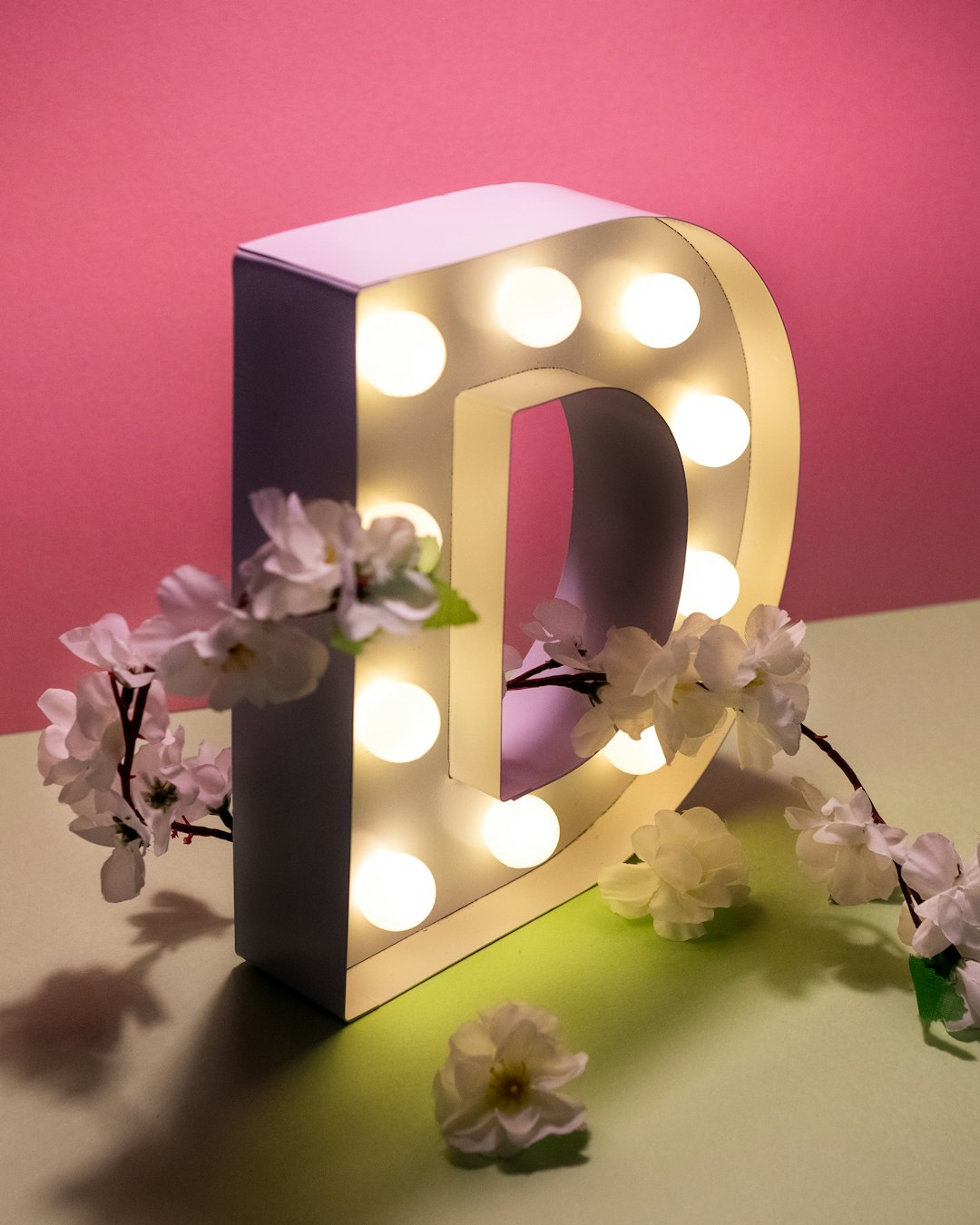 a-light-up-letter-with-flowers-on-a-table-4debmr80g9s